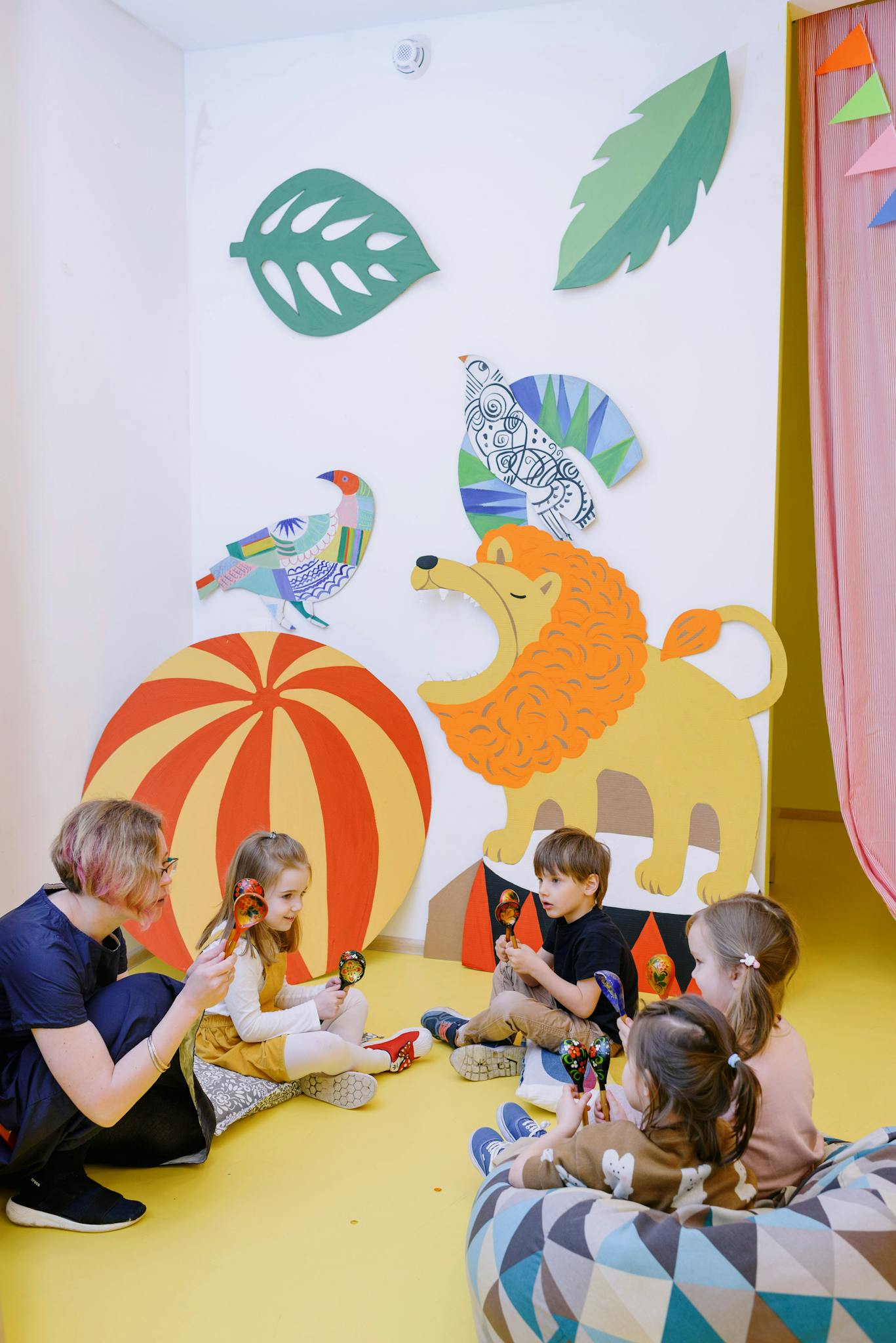A vibrant preschool classroom with children engaged in activities and playful wall art.